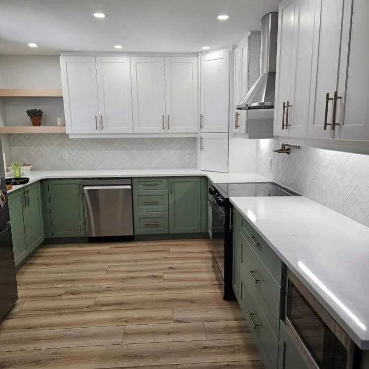 Sage green shaker kitchen with white uppers over wide plank flooring run through the room