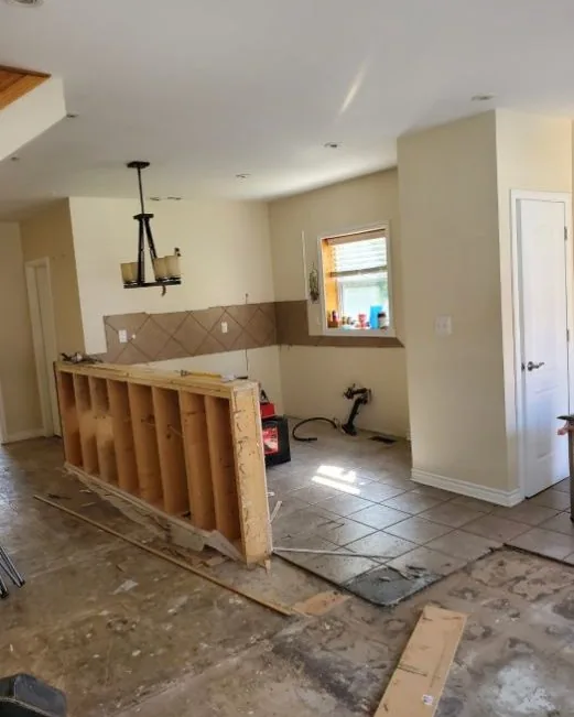 Before: the same kitchen stripped back to the subfloor with the old peninsula framing exposed