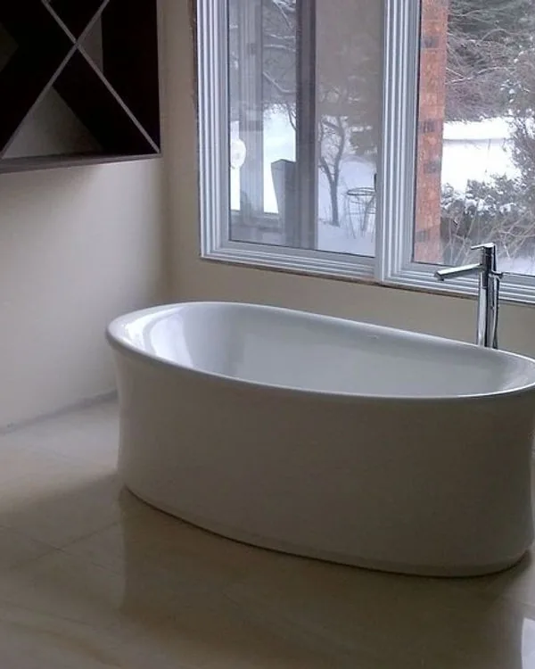 Freestanding soaker tub set in front of a window looking onto open country