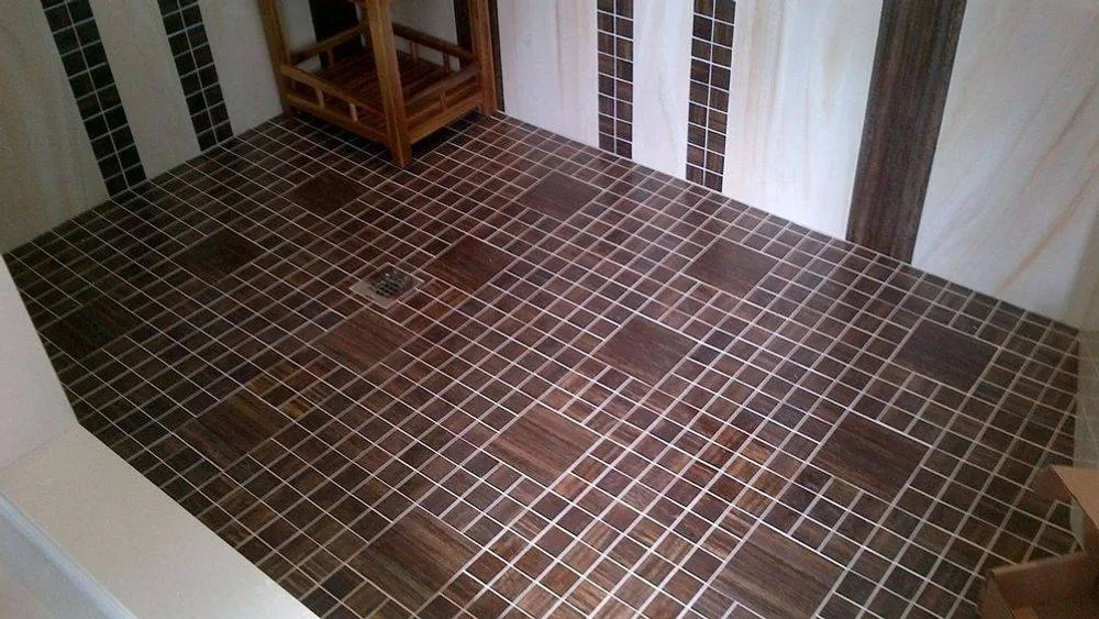 Shower floor in wood look mosaic tile with larger feature squares set into the pattern