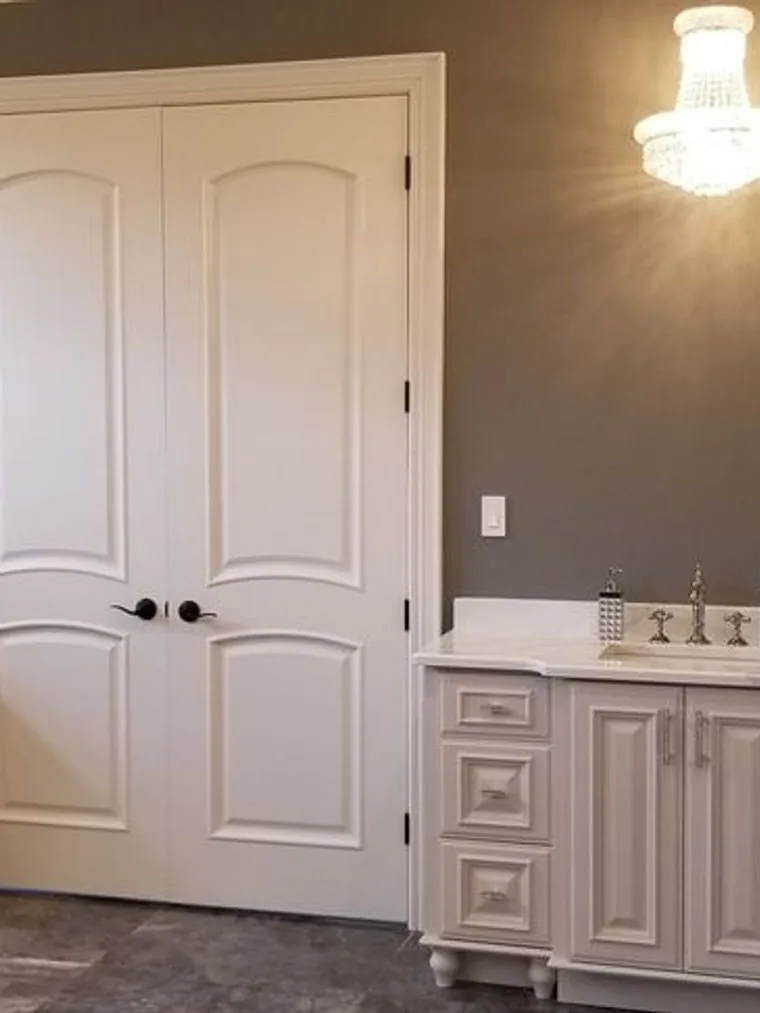 Furniture style vanity with a marble top beside panelled double doors