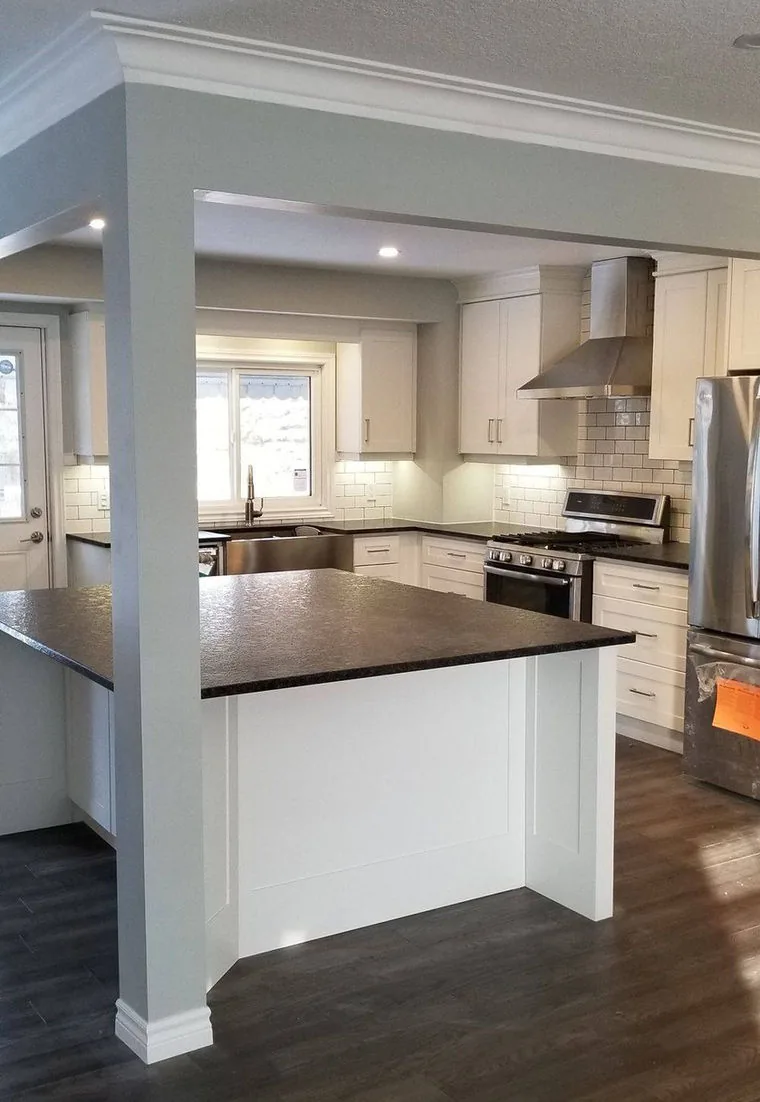 White custom kitchen with dark stone counters and a peninsula opened into the living room